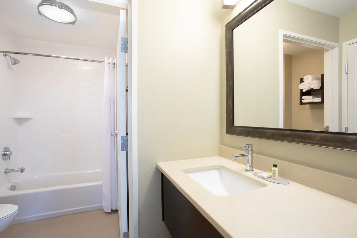 A serene bathroom scene featuring a large mirror, modern sink, and inviting bathtub, with soft lighting creating a refreshing and peaceful mood.
