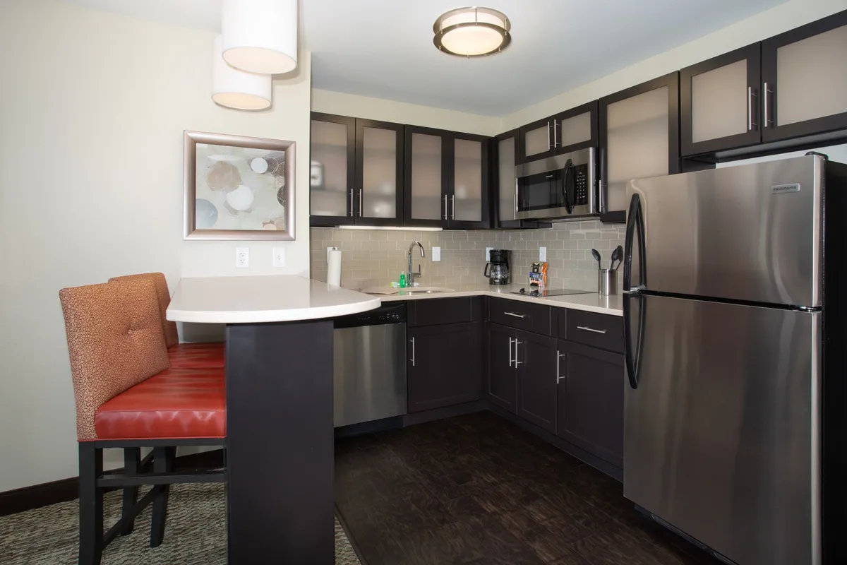 A cozy, contemporary kitchen featuring modern appliances including a stove, microwave, fridge, and dishwasher. Bar seating and decorative touches make it ideal for both cooking and casual dining.