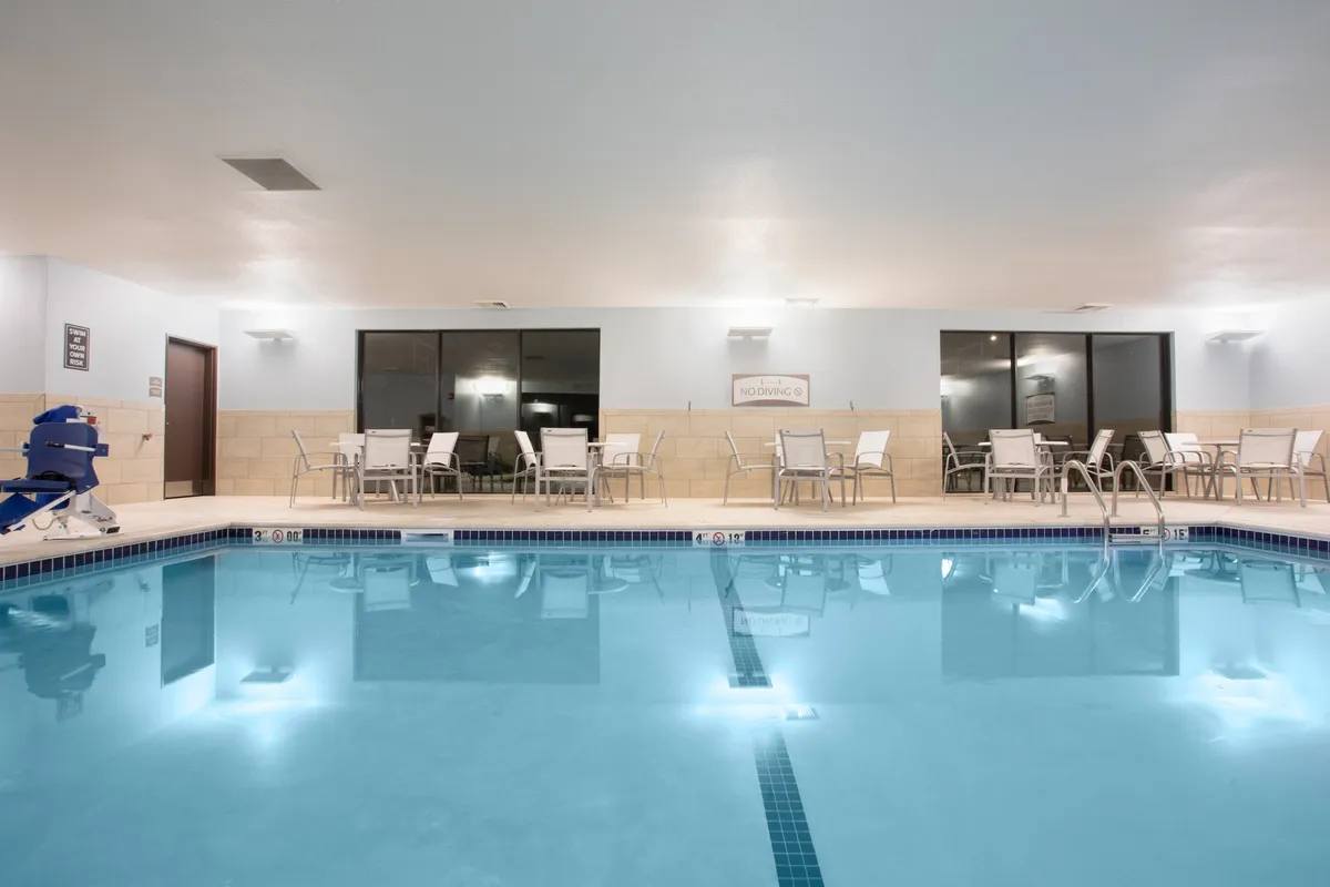 A calm, modern indoor pool area with comfortable seating and expansive windows, inviting guests to relax, swim, or socialize in a serene setting. The soft lighting suggests opportunities for late-night swims or casual poolside conversations.
