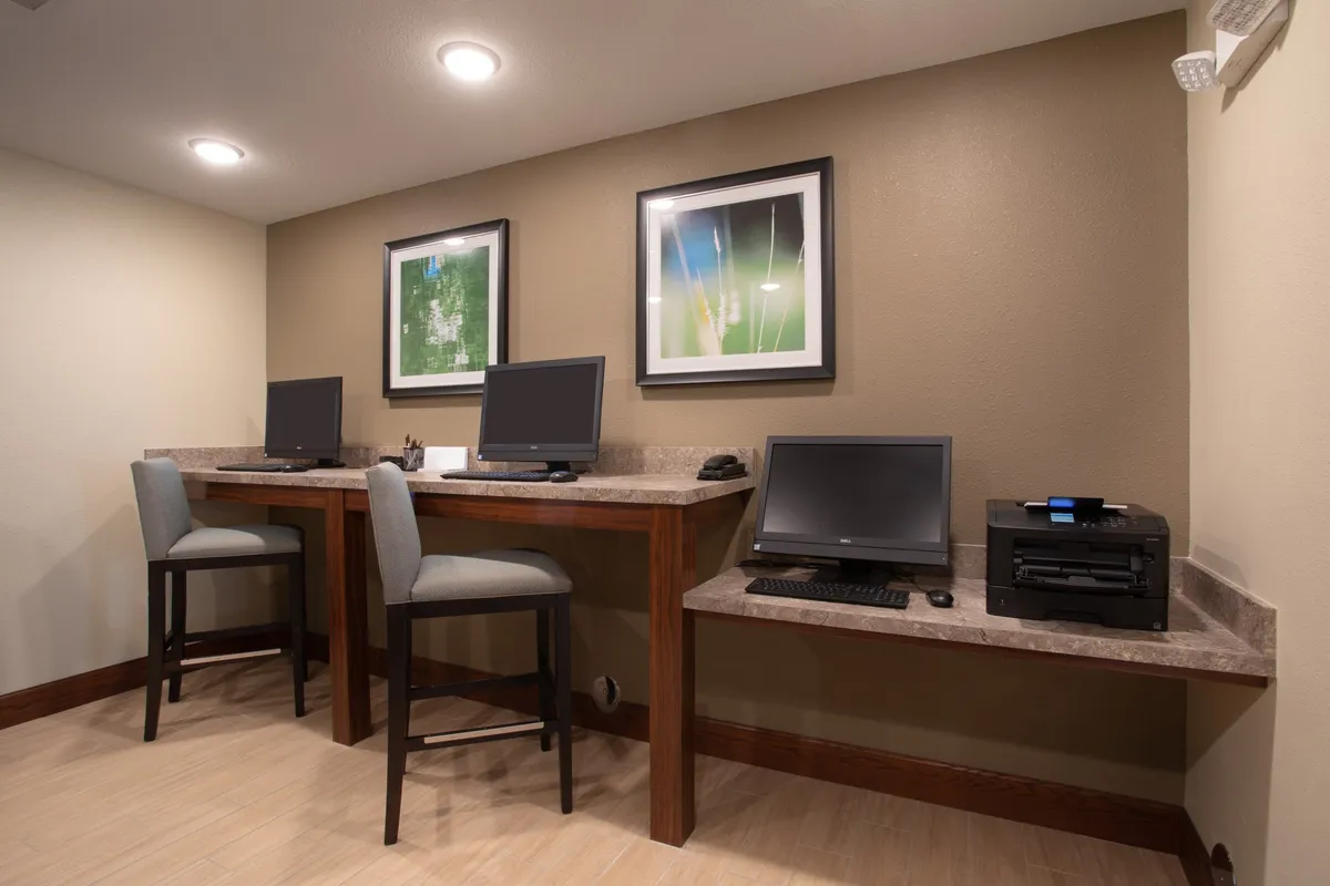 A compact and efficient workspace setup with computers, a printer, and framed artwork, ideal for productivity. The space is designed for focused work or study, highlighting a professional yet comfortable atmosphere.